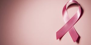 Pink breast cancer awareness ribbon on pink background